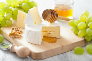 Board, cheese, grapes, honey, knife, nuts, spoon, white